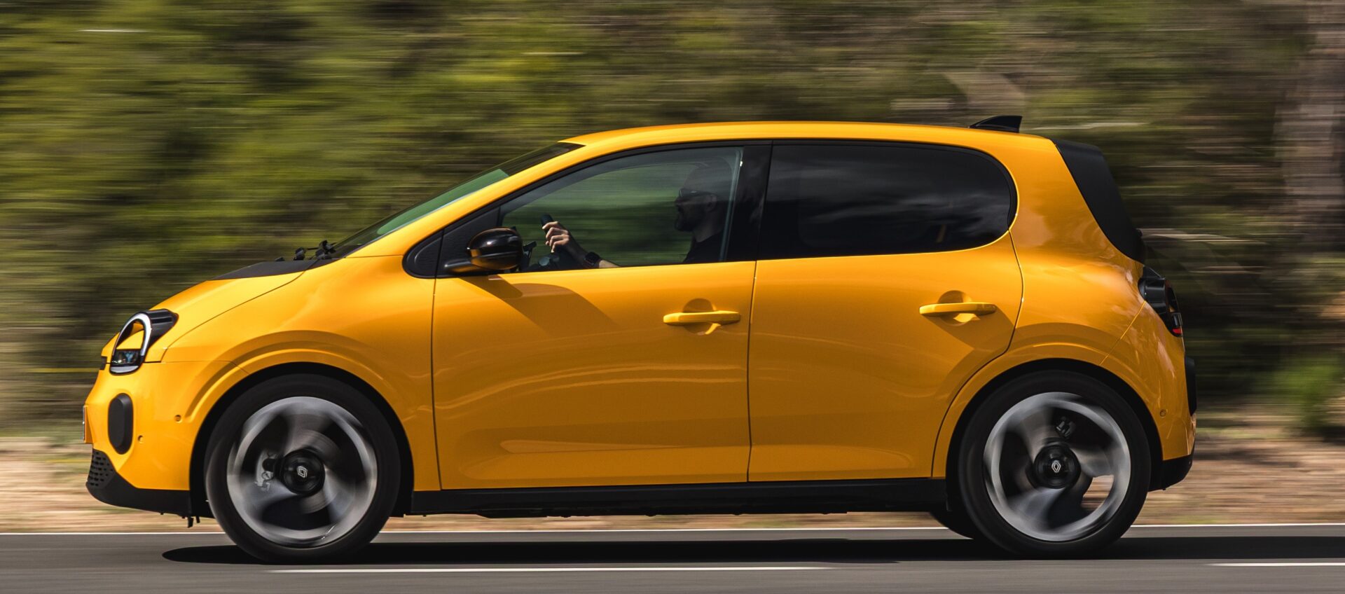 Renault Twingo E-Tech electric mango žute boje vozi se cestom kroz prirodu